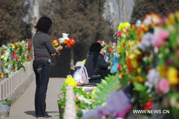 Citizens offer silk flowers as sacrifice to the deceased in a cemetery in Yinchuan, capital of northwest China's Ningxia Hui Autonomous Region, March 29, 2011. As the Tomb Sweeping Day approaches, which falls on April 5 this year, many people in Yinchuan chose to pay respect to the tombs of their deceased beloved ones with flowers instead of burning joss paper and setting off firecrackers which are harmful to environment. [Peng Zhaozhi/Xinhua]