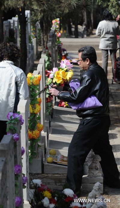 A man is seen holding a bunch of flowers in a cemetery in Beijing, capital of China, March 26, 2011, a few days ahead of China's traditional tomb-sweeping day on which Chinese memorized their beloved ones, on April 5th this year. (Xinhua/Li Wen) (cxy) 