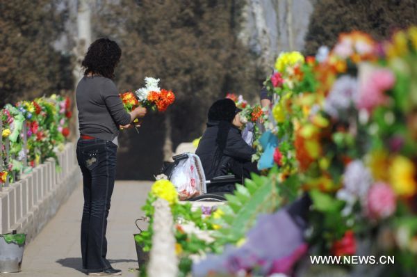 Citizens offer silk flowers as sacrifice to the deceased in a cemetery in Yinchuan, capital of northwest China's Ningxia Hui Autonomous Region, March 29, 2011. As the Tomb Sweeping Day approaches, which falls on April 5 this year, many people in Yinchuan chose to pay respect to the tombs of their deceased beloved ones with flowers instead of burning joss paper and setting off firecrackers which are harmful to environment. (Xinhua/Peng Zhaozhi) (llp) 