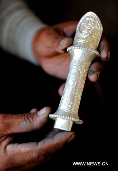 The Tibetan characters for Lnaze are seen on the knife, in Lnaze County of Xigaze Prefecture, southwest China's Tibet Autonomous Region, March 31, 2011. For 54-year-old craftsman Pudawa, inheritor of the Lnaze knife craftsmanship, nothing is happier than seeing his son Doje Zhamdu making better knife than his own. 'That means the craftsmanship of my family would pass onto the next generation. I am quite released. ' said the old Tibetan man. The Lnaze County, located at a remote region of Xigaze on the Qinghai-Tibet Plateau, is known for rich folk arts, such as the Tibetan tap dance and hand-made Tibetan knife. In 2008, the craftsmanship of Tibetan knife making in Lnaze County has been listed into China's National Intangible Cultural Heritages. Pudawa, being the sixth generation of a blacksmith family, is the most famous knife maker in the town. His knives always fail to meet growing demand as many Tibetans and tourists flock to his door asking for knives. Ten years ago, his son Doje Zhamdu began to learn the family skills. From the age of 18, he sat side by side with Pudawa, copying every step his father did, remembering all procedures in mind. Today he has become a knife maker as excellent as his father. However, he was quite reluctant to be a blacksmith at first. Like many young men in the town, he yearned for going outside as a migrant worker. 'In the old concept of Tibetans, blacksmith is a low-class career and not respected. People call us 'black bones'. ' said the son. But at last, the young man submitted to his father's wish to inherit the skills. Nowadays, with an annual family income of 26,000 yuan, much higher than the average, Doje felt happy about his choice. 'I am the eldest child in my family. I have to shoulder the responsibility to pass on the skills. Moreover, working at home with my father is convenient for taking care of the whole family.' Besides father and son, women also shoulder important responsibility in this family. Yexe Zhoima, the second daughter of Pudawa, weaves pulu, a traditional Tibetan-featured haircloth, at home, while Cering Quzhen, the elder daughter with blindness, studies at a government-funded special school in Lhasa. According to the Tibetan tradition, the family's craftsmanship can only pass on to male kin. Yixi Zhuoma likes watching her father and brother forging knives, but the only job she can do is cleaning the finished ones. 'I am proud of them.' She said with a smile while weaving pulu, which also brings a monthly income of 1,500 to the family. Though having a comfortable life and famous among people, Pudawa still has worries. The repute of Lnaze knife is now under great impact of massive machine-made knives sold on the market. As it takes a craftsman two to three days to forge a small-sized knife, even direct orders cannot be satisfied. In contrast, machine-made knives can be produced faster. 'I hope more people know about Lnaze knife and more young men learn the skills. Then people will not confuse real handmade knives with the fake ones,' said Pudawa, 'then I can truly retire from work and enjoy the rest of my life.' (Xinhua/Xu Yu) 