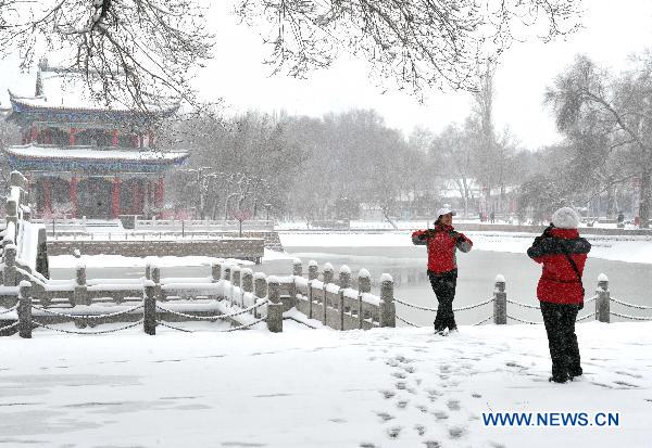 A resident poses for a photo in the snow at a park in downtown Urumqi, capital of northwest China&apos;s Xinjiang Uygur Autonomous Region, April 4, 2011. A heavy snow hit Urumqi Monday, where the temperature dropped to six degrees Celsius under zero.