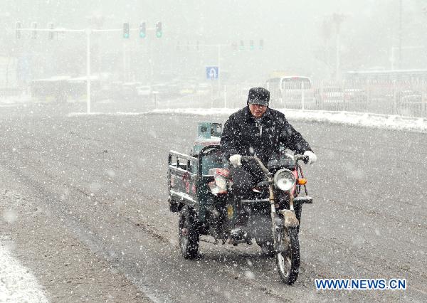 A deliverman drives a tricycle running in snow in downtown Urumqi, capital of northwest China&apos;s Xinjiang Uygur Autonomous Region, April 4, 2011. A heavy snow hit Urumqi Monday, where the temperature dropped to six degrees Celsius under zero. 