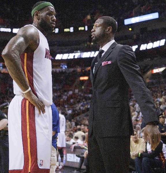 The Miami Heat's Forward Lebron James (L) talks with teammate Dwayne Wade, who did not dress for play because of injury, during a timeout against the Milwaukee Bucks in the first half of their NBA basketball game in Miami, Florida April 6, 2011. Bucks defeat Heat 90-85. (Xinhua/Reuters Photo)