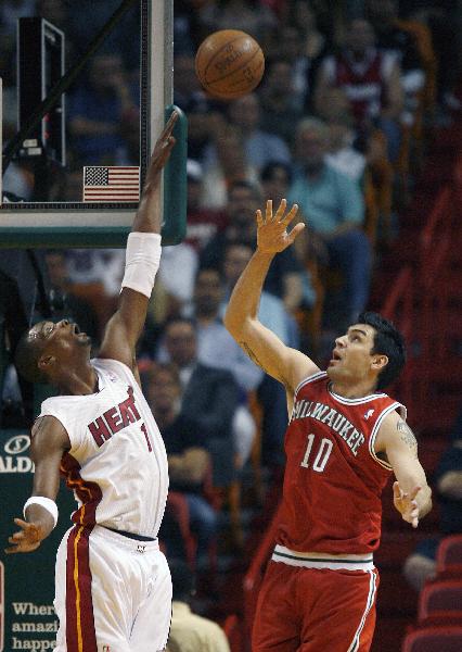 Miami Heat's forward Chris Bosh (L) defends as Milwaukee Bucks' forward/guard Carlos Delfino shoots in the first half of their NBA basketball game in Miami, Florida April 6, 2011. (Xinhua/Reuters Photo) 