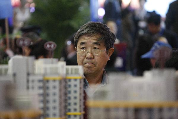 A visitor looks on in front of a sand table model at the 2011 Dalian Spring Realestate Trade Fair in Dalian, northeast China's Liaoning Province, April 8, 2011. (Xinhua/Chen Hao)