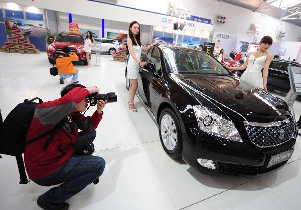 A man takes photo of an exhibited car at an auto show in Yantai of east China's Shandong Province, April 8, 2011. A total of 700 automobiles from 69 brands were displayed in the exhibition.(Xinhua/Chu Yang)(xzj) 
