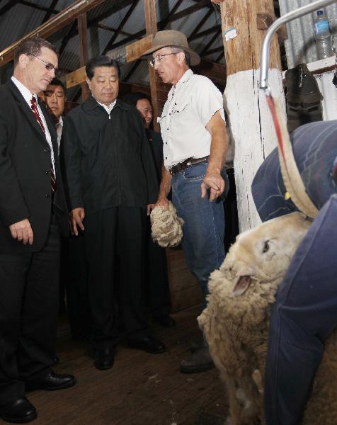 Jia Qinglin, chairman of the National Committee of the Chinese People's Political Consultative Conference, watches a worker shearing a sheep during his visit to a ranch run by Ian Cusack in Canberra, Australia, April 8, 2011. (Xinhua/Liu Weibing) 