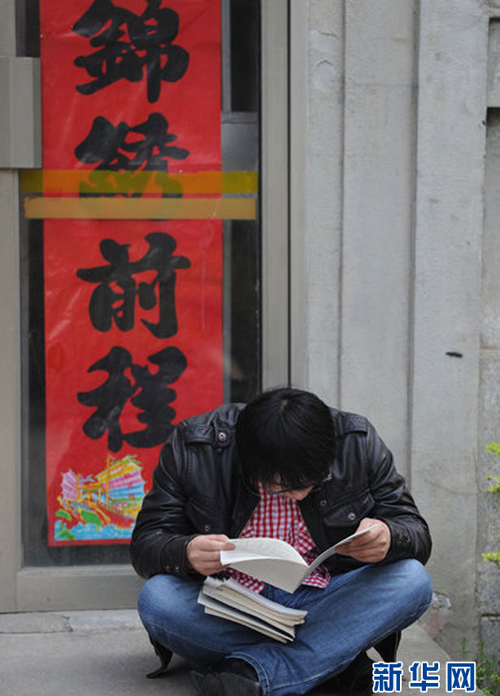 A candidate takes a quick glimpse at lecture notes at an exam site in Hefei, east China's Anhui Province, April 10, 2011, before the start of the 2011 Anhui Provincial Public Servant Exam. [Photo/Xinhua] 