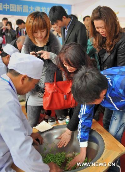 Travelling merchants experience the stir-frying of the Longjing (Dragon Well) Tea during a tea fair held in Xinchang County, east China's Zhejiang Province, April 11, 2011. 