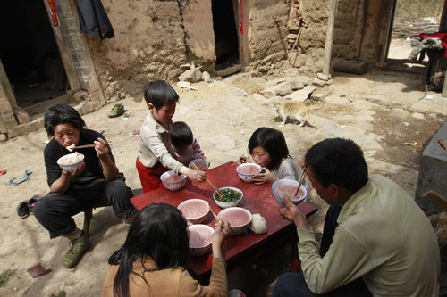 Yuan Tieming and his wife eat lunch together with four of their girls in their courtyard in Sunyuan village of Luoyang city, Central China's Henan province, April 10, 2011.