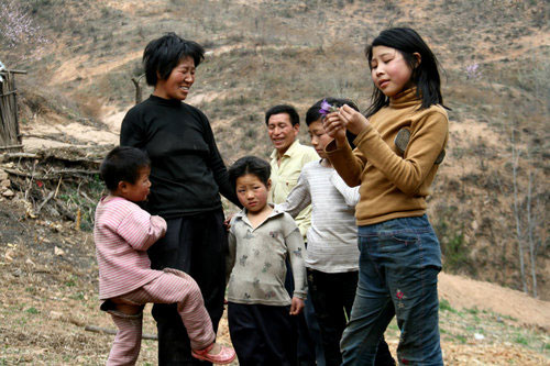 Yuan Tieming and his wife together with four of their girls play in front of their house in Sunyuan village of Luoyang city, Central China's Henan province, April 10, 2011. 
