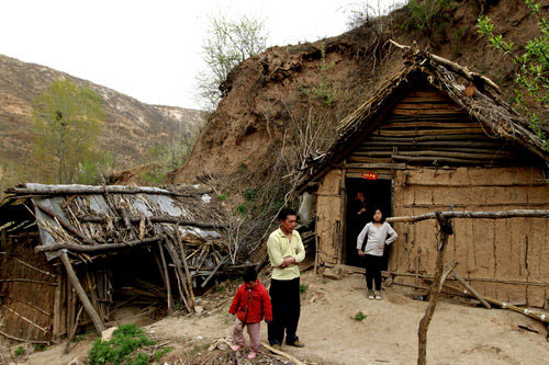 Yuan Tieming and two of his girls stand in front of their house in a remote hill in Sunyuan village of Luoyang city, Central China's Henan province, April 10, 2011. 