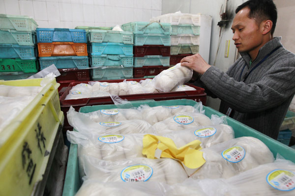 A law enforcement official seals packages of impounded steamed buns on Tuesday at a production facility belonging to the Shanghai Shenglu Food Company, which allegedly used an illegal color additive to dye buns. [Photo/Xinhua]