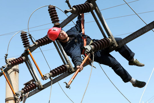 A technician checks a high-tension wire on April 11 to ensure that mineshafts at a coal mine company in Huaibei, Anhui province, are receiving power in a safe way. [Huang Shipeng/China Daily]