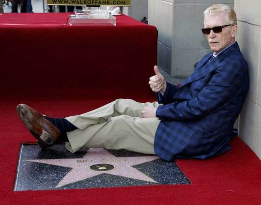 CBS news correspondent and author Bill Geist poses as he sits beside his newly unveiled star on the Hollywood Walk of Fame in Hollywood, California April 15, 2011. [Xinhua/Reuters]