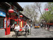 Two people riding three-wheeled bicycle in Nanluoguxiang. [China.org.cn by Li Xiaohua]