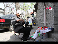 An old woman selling traditional crafts in Nanluoguxiang. [China.org.cn by Li Xiaohua]