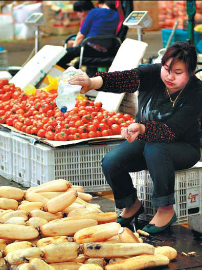 A stall owner waters lotus roots to keep them fresh at a marketplace in Nanjing, Jiangsu province. Rising inflation, especially in food and vegetable prices, may lead to more government actions, UBS said on Monday. [China Daily]