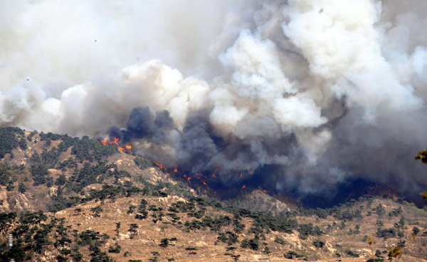 Fire and smoke engulf part of a mountain near Shandong's capital city of Jinan, spreading toward Mount Tai, April 18, 2011. [Xinhua]  