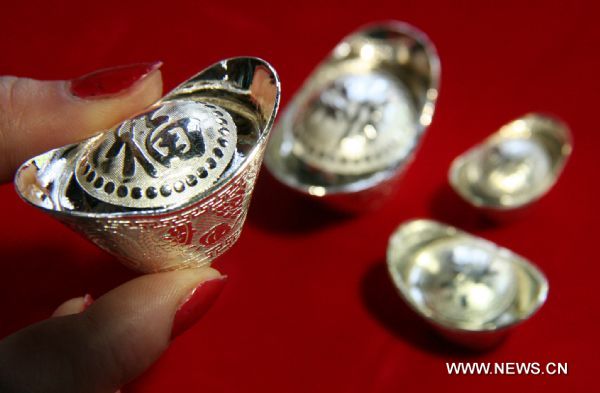 A sales clerk holds a silver ingot at a jewelry shop in Linyi City, east China's Shandong Province, April 18, 2011. Silver prices have soared by over 1,000 yuan per kilogram so far this month, to stand above 9,000 yuan per kilogram. (1 U.S. dollar=6.53 yuan) 