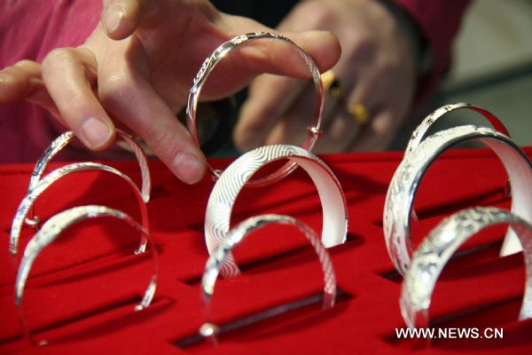 A sales clerk holds a silver bracelet at a jewelry shop in Linyi City, east China's Shandong Province, April 18, 2011. Silver prices have soared by over 1,000 yuan per kilogram so far this month, to stand above 9,000 yuan per kilogram. (1 U.S. dollar=6.53 yuan) 