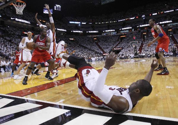 Miami Heat shooting guard Dwyane Wade (below) falls to the floor after losing the ball to Philadelphia 76ers power forward Elton Brand (2nd L) in the first quarter during their NBA Eastern Conference playoff series in Miami April 18, 2011. (Xinhua/Reuters Photo)