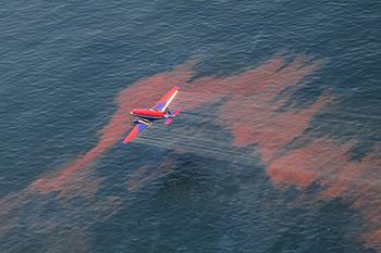 An aircraft releases dispersant over an oil discharge from the Deepwater Horizon off the shore of Louisiana, May 5, 2010. [U.S. Coast Guard] 