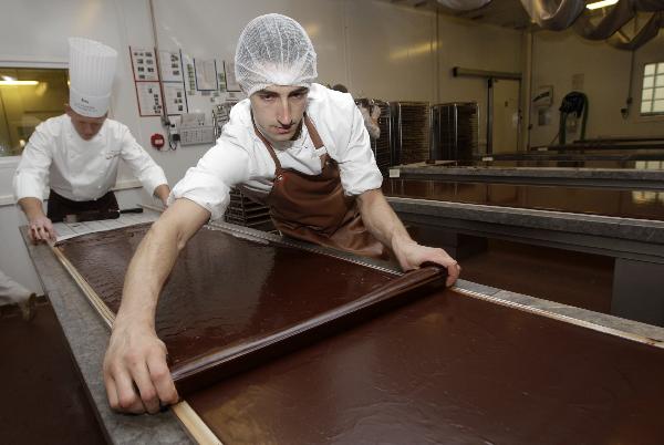 La Maison du Chocolat's creative director Gilles Marchal (L) assists an employee as they spread chocolate in preparation for Easter creations at their workshop in Nanterre, near Paris April 20, 2011. Some 13,000 tonnes of chocolate are sold in France during the Easter holiday period, which counts for 3.5 percent of total yearly sales or even more for luxury chocolate stores. [Xinhua/Reuters]