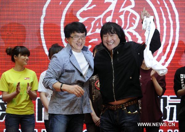 Movie star Jackie Chan (L front) gives a T-shirt with his autograph to his fan at the opening ceremony of the cinema named after him in Shenyang, capital of northeast China's Liaoning Province, April 20, 2011. The Jackie Chan Theatre International, a cinema chain in China, started business in Shenyang and donated 1.2 million RMB (184,000 US dollars) to local charity projects Wednesday. [Wang Jiang/Xinhua]