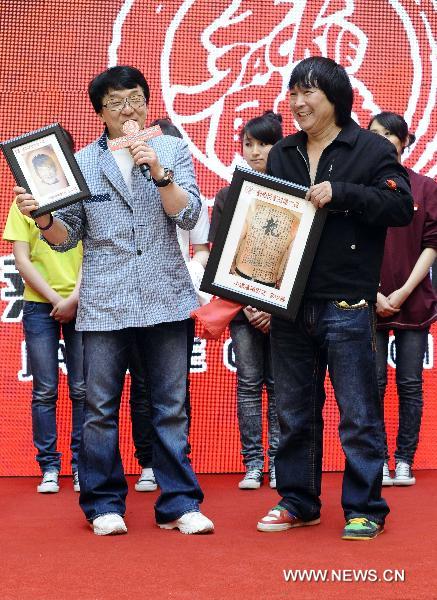 Movie star Jackie Chan (L front) receives gifts from his fan at the opening ceremony of the cinema named after him in Shenyang, capital of northeast China's Liaoning Province, April 20, 2011. [Yang Qing/Xinhua]