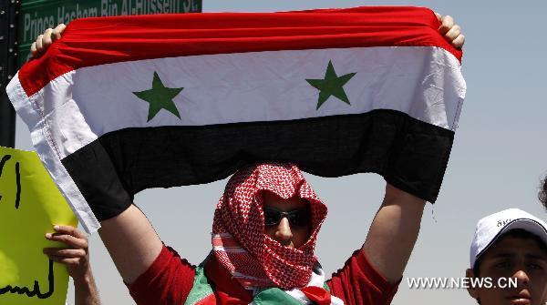 A Syrian protester holds up a Syrian national flag during a demonstration attended by Syrians living in Jordan against Bashar's government and the ruling Baath Party in front of Syrian embassy in Amman, capital of Jordan, on April 24, 2011.[Mohammad Abu Ghosh/Xinhua]