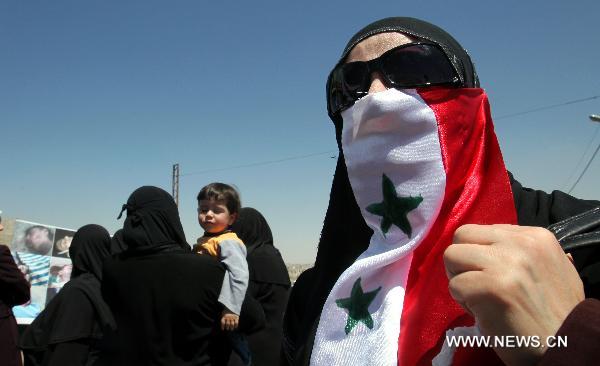 A Syrian female protester veils her face with a Syrian national flag during a demonstration attended by Syrians living in Jordan against Bashar's government and the ruling Baath Party in front of Syrian embassy in Amman, capital of Jordan, on April 24, 2011. [Mohammad Abu Ghosh/Xinhua]