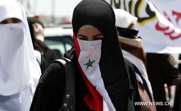 A Syrian female protester veils her face with a Syrian national flag during a demonstration attended by Syrians living in Jordan against Bashar's government and the ruling Baath Party in front of Syrian embassy in Amman, capital of Jordan, on April 24, 2011. [Mohammad Abu Ghosh/Xinhua] 