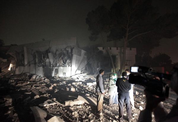 People talk near a damaged building at Muammar Gaddafi's Bab al-Aziziya compound in Tripoli April 25, 2011. [Xinhua]