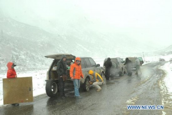 A driver tries to replace a tyre for his vehicle on the ice and snow-covered national road linking Garze County and Dege County in southwest China&apos;s Sichuan Province, April 23, 2011. Due to the continuous snowfall, the Garze-Dege section of National Road 317 which links Sichuan and neighboring Tibet Autonomous Region was covered with snow of over 50 cm in thickness, causing many vehicles stranded for hours. 