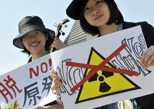 Protestors hold a banner and placards as they protest against Japan&apos;s nuclear policy during a parade for the Earth Day in Tokyo on April 24, 2011. Hundreds of people joined the march &apos;Energy Shift Parade,&apos; demanding the use of sustainable energy instead of nuclear power. [Xinhua/AFP] 