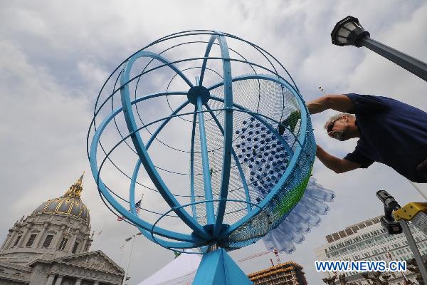 A man uses recycled bottles to build an earth model during a promotion of the Earth Day in San Francisco, the United States, April 23, 2011. 
