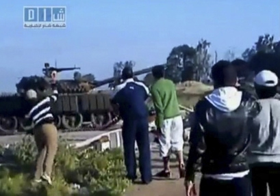 A Syrian youth is hurling stones at an armored vehicle in the town of Daraa. 