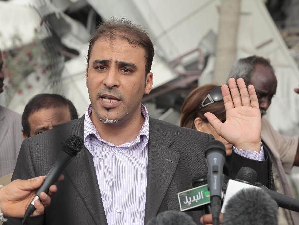 Mussa Ibrahim, a Libyan government spokesman, holds a news conference near a damaged building at Libyan leader Muammar Gaddafi&apos;s Bab al-Aziziyah compound in Tripoli April 25, 2011. Gaddafi was unhurt in a NATO airstrike on his Bab al-Aziziyah compound early on Monday that left three people dead, Ibrahim said. [Xinhua]