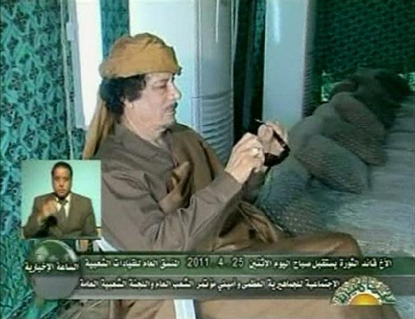 Libyan leader Muammar Gaddafi looks at his sunglasses as he meets with leaders of the Social Committee of the People, hours after NATO forces flatten a building inside his Bab al-Aziziyah compound, in a pitched tent in Tripoli in this still image taken from video April 25, 2011. [Xinhua] 