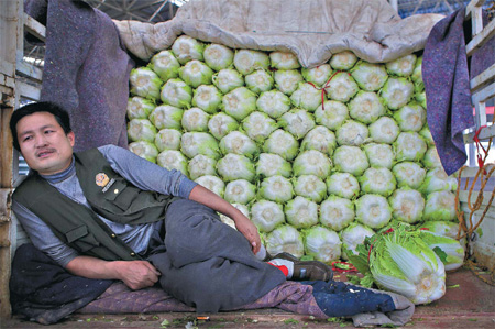 Chen Jianquan, 32, a farmer from Qingzhou city, Shandong province, waits in his truck at one of China's largest vegetable wholesale markets in Shouguang. It was Saturday afternoon, and Chen had arrived with a ton of Chinese cabbage at 1 am. Most of it still had not been sold. [China Daily]