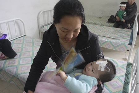 A woman takes care of her baby, who fell sick after drinking tap water contaminated by e-coli bacteria, at the people's hospital in Yilan county, Heilongjiang province, on Sunday. [China Daily] 