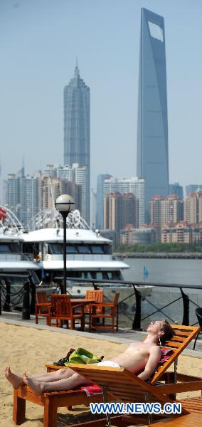 A tourist enjoys sun bath on an artificial sand beach at the South Bund in Shanghai, east China, April 26, 2011. The temperature in Shanghai rose quickly to hit 33.2 degrees Celsius in downtown area on Tuesday. [Xinhua] 