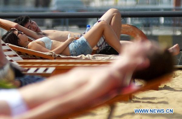 Tourists enjoy sun bath on an artificial sand beach at the South Bund in Shanghai, east China, April 26, 2011. The temperature in Shanghai rose quickly to hit 33.2 degrees Celsius in downtown area on Tuesday. 