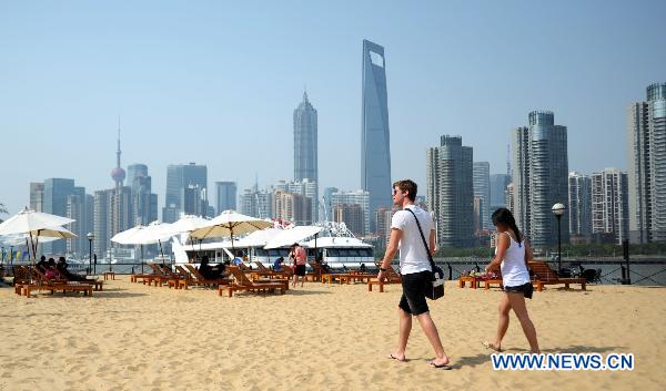 Tourists walk on an artificial sand beach at the South Bund in Shanghai, east China, April 26, 2011. The temperature in Shanghai rose quickly to hit 33.2 degrees Celsius in downtown area on Tuesday. 