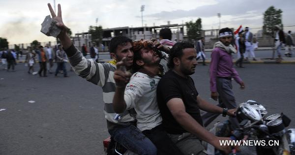 Anti-government protesters carry a wounded to the hospital during the clashes in Sanaa, capital of Yemen, April 27, 2011. Death toll from clashes between anti-government protesters and police, government backers in the capital Sanaa on Wednesday rose to 12, and 160 protesters were injured, doctors said on Wednesday. [Xinhua]