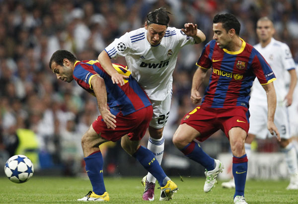 Barcelona's Xavi Hernandez (R) and Javier Mascherano (L) fight for the ball with Real Madrid's Mesut Ozil during their Champions League semi-final first leg soccer match at Santiago Bernabeu stadium in Madrid, April 27, 2011. (Xinhua/Reuters Photo)