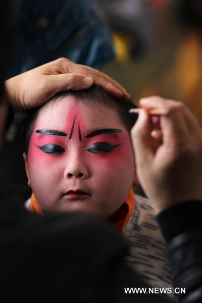  Teacher Li Pengshan applies makeup to the face of Cheng Bin in Nantong, east China's Jiangsu Province, April 16, 2011. The ten-year-old Cheng Bin is a pupil of the Chenqiao Primary School, a small rural school in Nantong. He and some 200 pupils of the school started to learn Peking Opera when they are in the first grade. When attired in various costumes, moving with agility in thick-soled performance boots and colored greasepaint on his face, Cheng becomes a powerful 'magnet' that attracts the audience. Despite his increasing popularity among the audience in east China's Jiangsu Province where he was born, the chubby boy has his vexations, not least his 37.5-kg body weight which is unbecoming to his age and his 1.29-meter height. In the eyes of others, Cheng Bin is a lovable Humpty-Dumpty. However, obesity has posed an obstacle in his pursuit of becoming a professional Peking Opera actor. Each time when he attended Peking Opera course in which action trainings were given, Cheng would have to make greater efforts than his fellows. During a training session which usually involved rolling, jumping, kneeling and doing horizontal splits, Cheng would be soaked in sweat two or three times. 'The boy has a talent for stage performance, good understanding of the characters and fine vocal conditions. He will have better career prospect if he loses weight,' says Li Pengshan, a famous actor who chose Cheng as his disciple when the kindergarten boy's performance impressed him in 2006. With the possibility of failing to realize his dream looming large, Cheng made up his mind to battle against obesity and a series of tough moves have been taken since April. He went on diet and gave up greasy and spicy dishes he used to love; he walked four kilometers to school and back home each day; and he did various physical exercises after school. Cheng's mother is a worker in a brewery in Nantong and his father works for a local construction company. In March of last year, the couple planed to break off their son's Peking Opera course, which are in conflict with his primary school education. But they eventually changed their mind. 'We are really thankful to the instructors who devoted so much to our son and we are also touched by our son's determination,' says Yang Lihong, Cheng's mother. 'The best we can do is to offer full support.' 'If you want to achieve something, you must first conquer yourself.' The line from the film 'Farewell My Concubine' is Cheng's motto. Last August, Cheng was awarded second prize in a provincial children's Peking Opera competition in Jiangsu after beating over 300 competitors. In May, 2011, he will be taking part in a national-level children's Peking Opera competition held in Nanjing, capital of east China's Jiangsu Province. (Xinhua/Huang Zhe) (ljh) 
