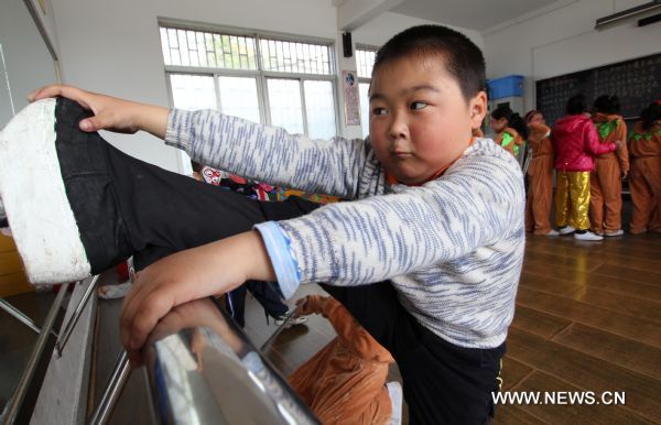 Cheng Bin does extra splits after a Peking Opera training session in Nantong, east China's Jiangsu Province, April 16, 2011. The ten-year-old Cheng Bin is a pupil of the Chenqiao Primary School, a small rural school in Nantong. He and some 200 pupils of the school started to learn Peking Opera when they are in the first grade. When attired in various costumes, moving with agility in thick-soled performance boots and colored greasepaint on his face, Cheng becomes a powerful 'magnet' that attracts the audience. Despite his increasing popularity among the audience in east China's Jiangsu Province where he was born, the chubby boy has his vexations, not least his 37.5-kg body weight which is unbecoming to his age and his 1.29-meter height. In the eyes of others, Cheng Bin is a lovable Humpty-Dumpty. However, obesity has posed an obstacle in his pursuit of becoming a professional Peking Opera actor. Each time when he attended Peking Opera course in which action trainings were given, Cheng would have to make greater efforts than his fellows. During a training session which usually involved rolling, jumping, kneeling and doing horizontal splits, Cheng would be soaked in sweat two or three times. 'The boy has a talent for stage performance, good understanding of the characters and fine vocal conditions. He will have better career prospect if he loses weight,' says Li Pengshan, a famous actor who chose Cheng as his disciple when the kindergarten boy's performance impressed him in 2006. With the possibility of failing to realize his dream looming large, Cheng made up his mind to battle against obesity and a series of tough moves have been taken since April. He went on diet and gave up greasy and spicy dishes he used to love; he walked four kilometers to school and back home each day; and he did various physical exercises after school. Cheng's mother is a worker in a brewery in Nantong and his father works for a local construction company. In March of last year, the couple planed to break off their son's Peking Opera course, which are in conflict with his primary school education. But they eventually changed their mind. 'We are really thankful to the instructors who devoted so much to our son and we are also touched by our son's determination,' says Yang Lihong, Cheng's mother. 'The best we can do is to offer full support.' 'If you want to achieve something, you must first conquer yourself.' The line from the film 'Farewell My Concubine' is Cheng's motto. Last August, Cheng was awarded second prize in a provincial children's Peking Opera competition in Jiangsu after beating over 300 competitors. In May, 2011, he will be taking part in a national-level children's Peking Opera competition held in Nanjing, capital of east China's Jiangsu Province. (Xinhua/Huang Zhe) (ljh) 