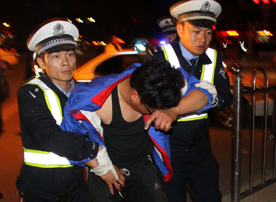 Two traffic police officers in Xingtai, Hebei province, help a man suspected of drunk driving take a blood test on Sunday. [China Daily]